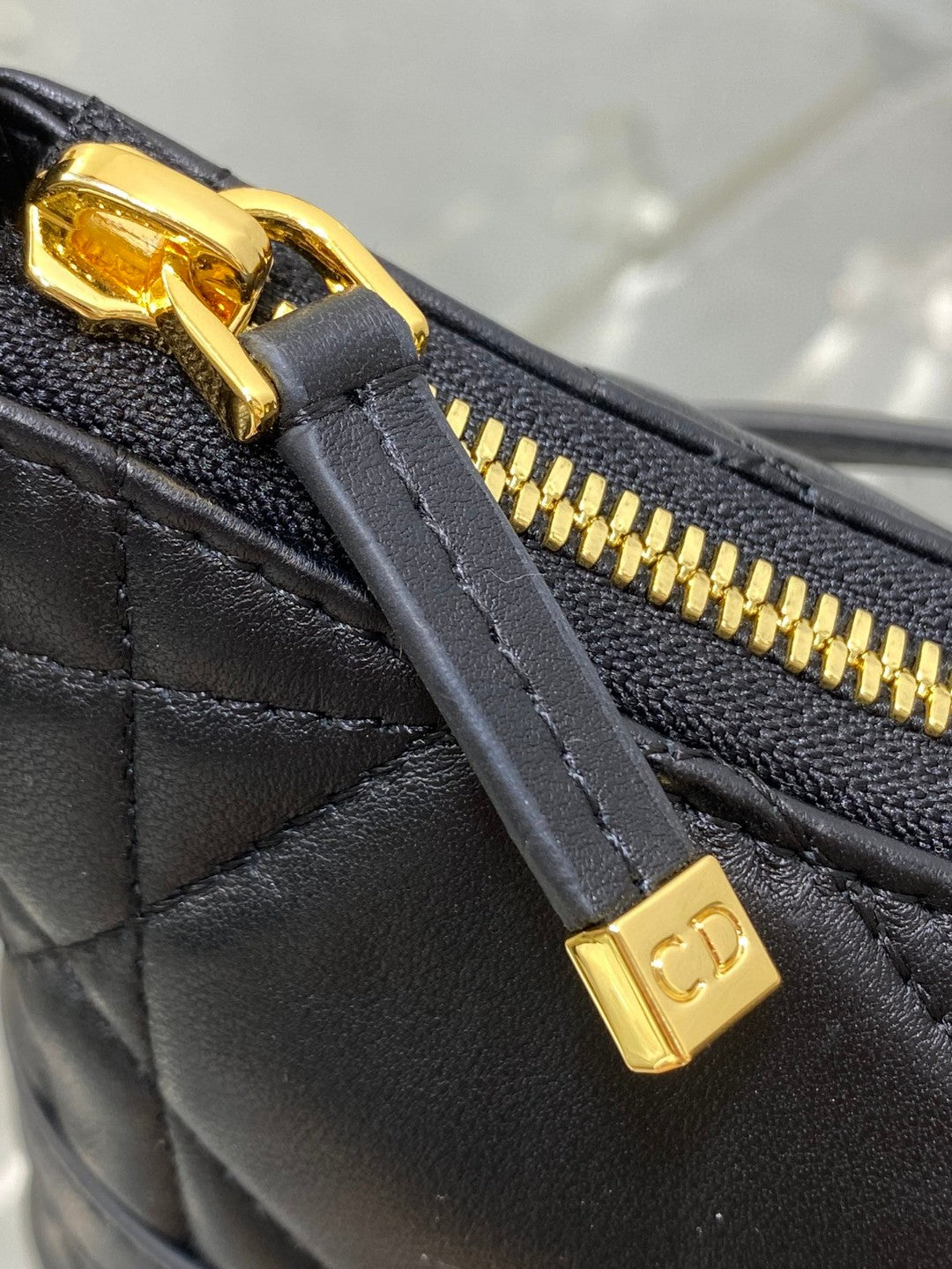 Dior Miss Caro mini hobo shoulder bag in black Macrocannage lambskin with a gold-finish metal CD signature and chain strap.