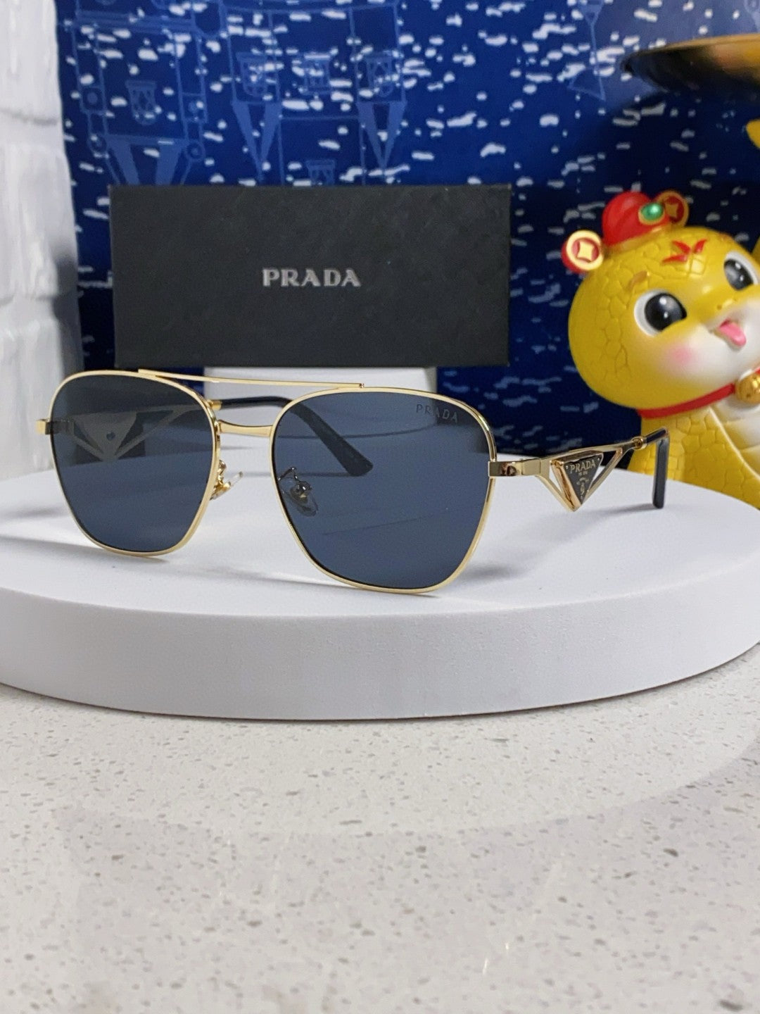 Prada aviator sunglasses with a gold metal frame and blue/grey lenses