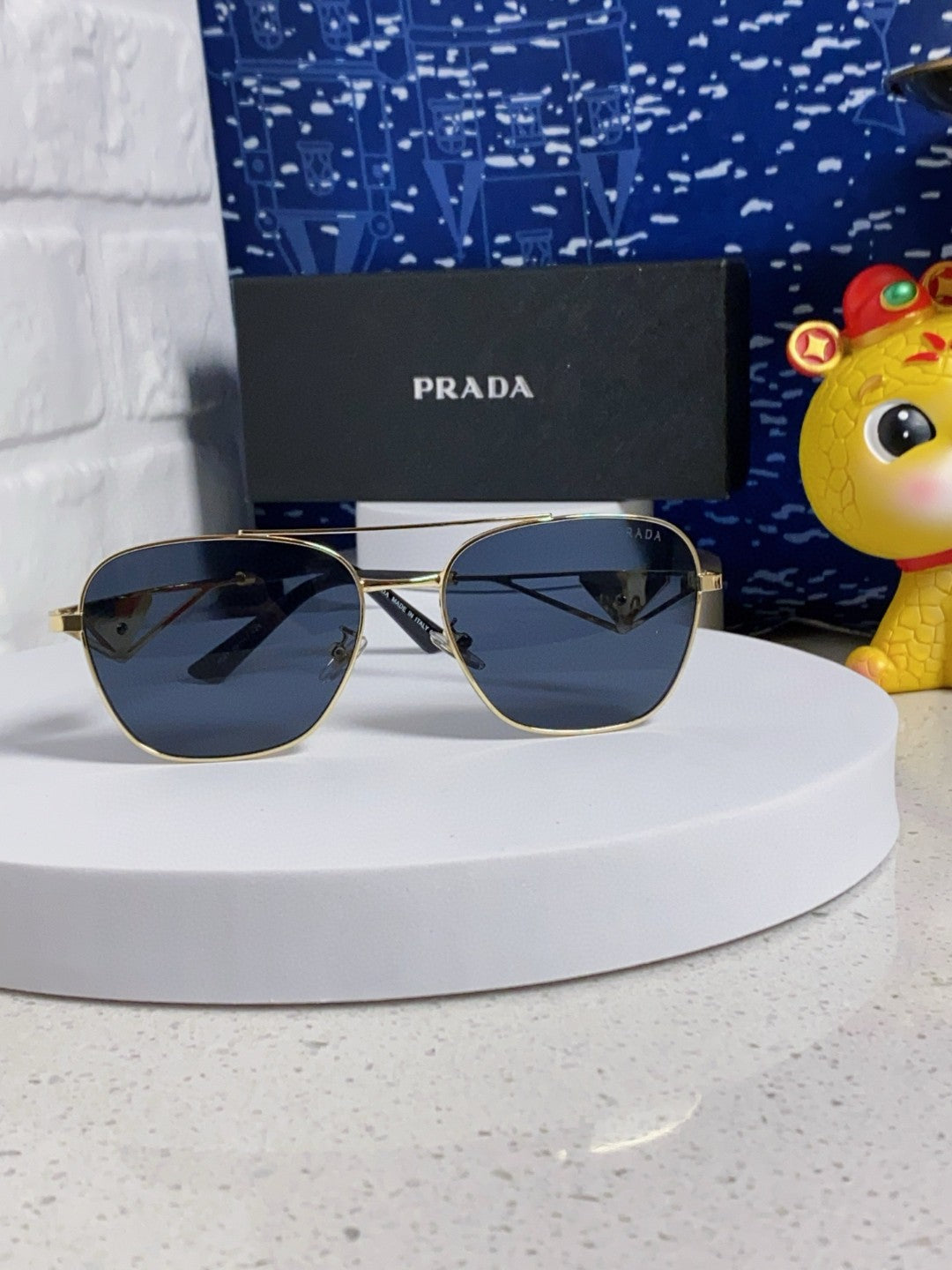 Prada aviator sunglasses with a gold metal frame and blue/grey lenses