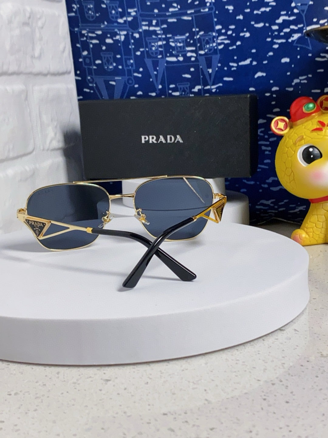Prada aviator sunglasses with a gold metal frame and blue/grey lenses