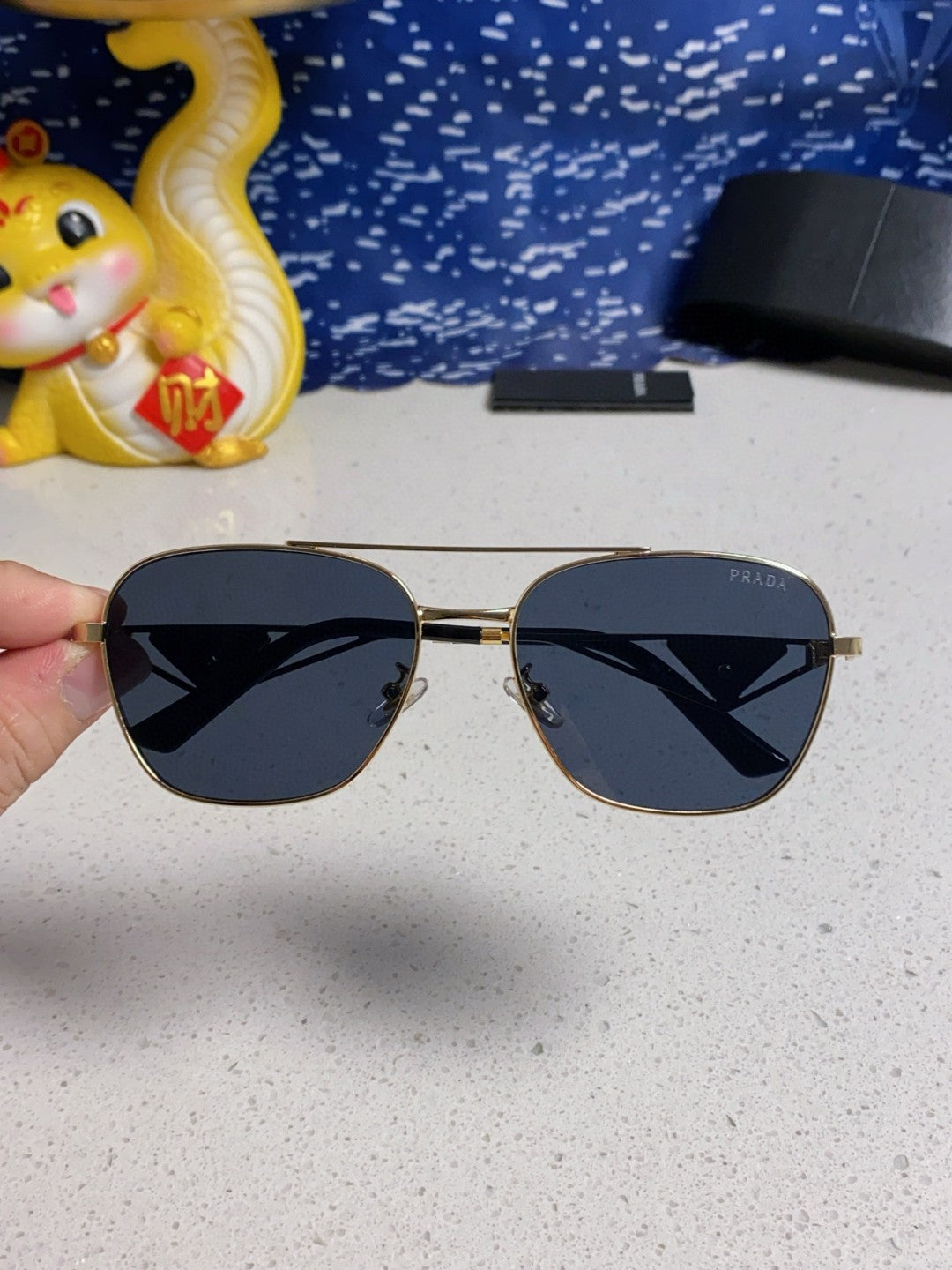 Prada aviator sunglasses with a gold metal frame and blue/grey lenses