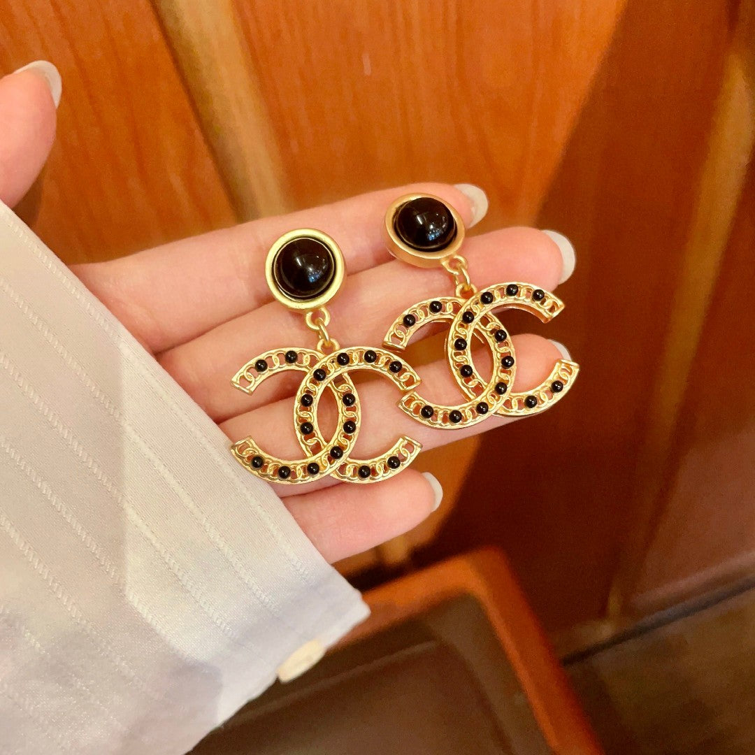 Chanel CC logo drop earrings in black and gold tone metal with black onyx studs and rhinestone embellishments