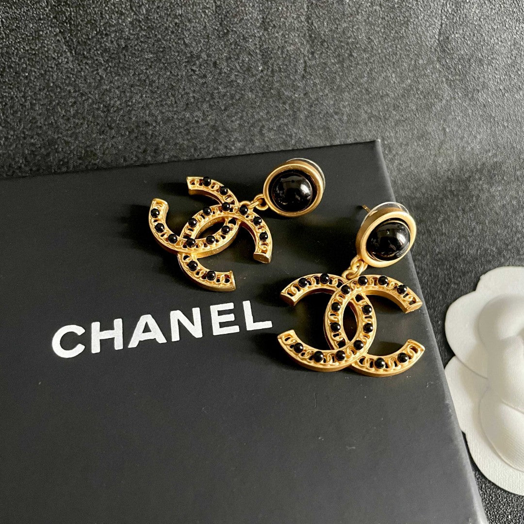 Chanel CC logo drop earrings in black and gold tone metal with black onyx studs and rhinestone embellishments