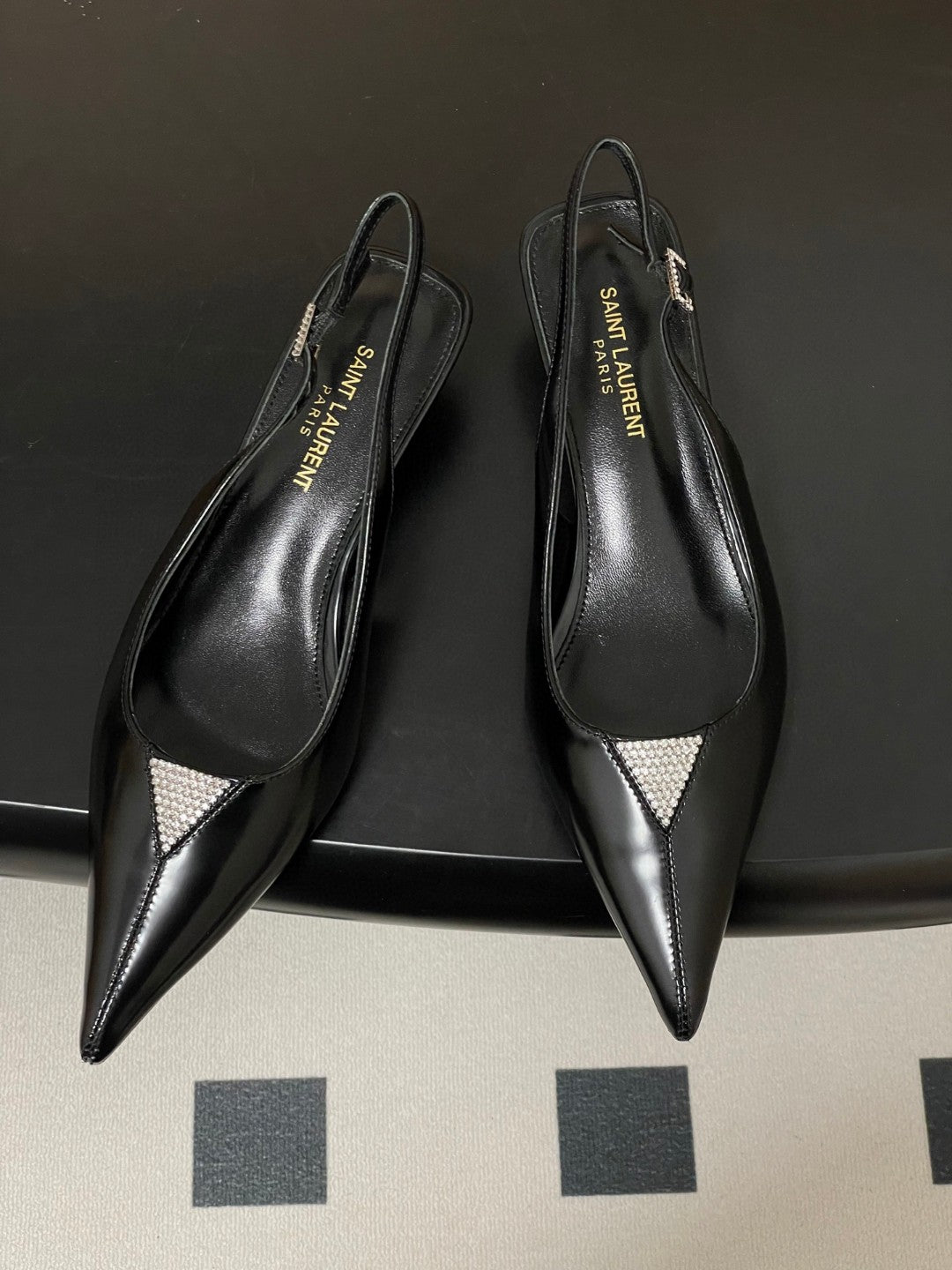 Saint Laurent Cherish 30 slingback pumps in black glazed calfskin leather with a rhinestone triangle detail